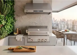 Churrasqueira a gás embutida em varanda gourmet de apartamento com coifa inox e ventilação adequada, integrada a área externa com vista urbana.