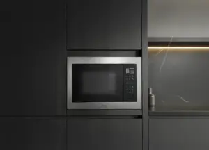 Micro-ondas de embutir em inox integrado à marcenaria escura de cozinha planejada contemporânea, com acabamento minimalista e iluminação indireta ao fundo.